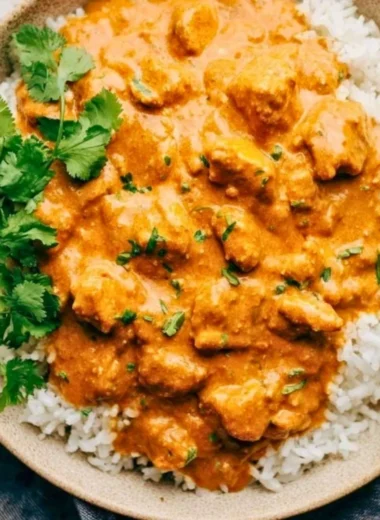 Delicious crockpot butter chicken served with rice and herbs.