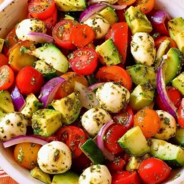 Tomato Cucumber Salad with avocado, mozzarella, and basil pesto in a bowl