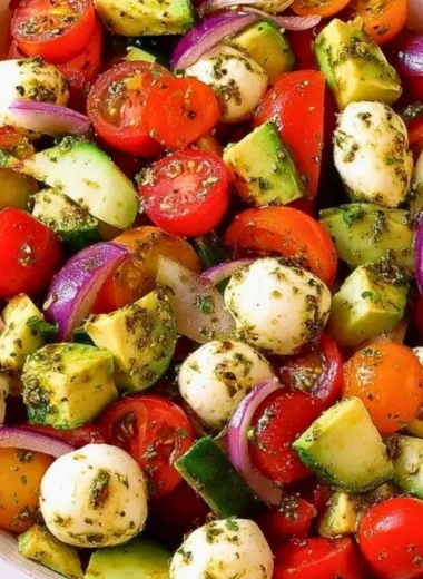 Tomato Cucumber Salad with avocado, mozzarella, and basil pesto in a bowl