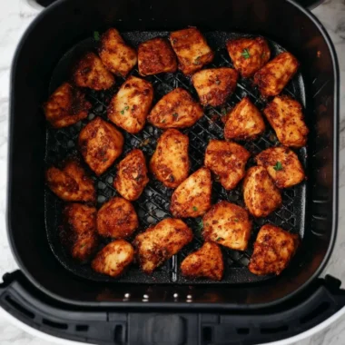 Crispy air fryer chicken bites served with dipping sauce on a plate.