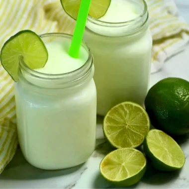 Glass of Brazilian Lemonade with Coconut served with fresh limes