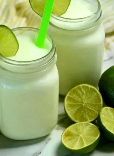 Glass of Brazilian Lemonade with Coconut served with fresh limes