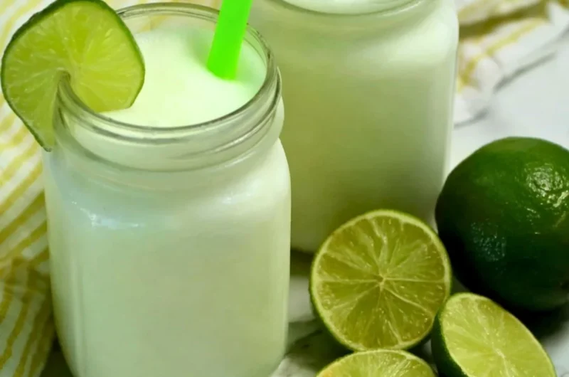 Glass of Brazilian Lemonade with Coconut served with fresh limes