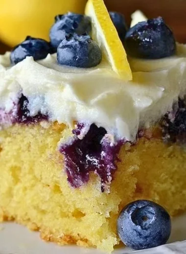 Delicious Lemon Blueberry Poke Cake topped with fresh blueberries.
