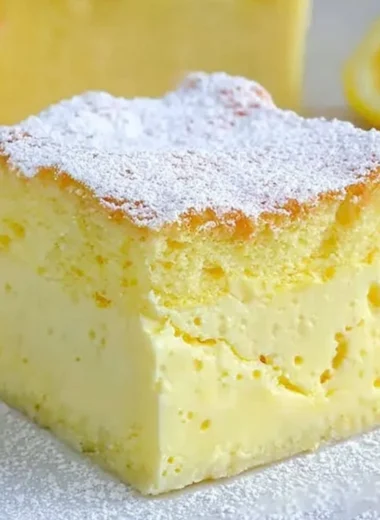 A slice of cozy magic lemon custard cake with lemon garnish on a white plate.