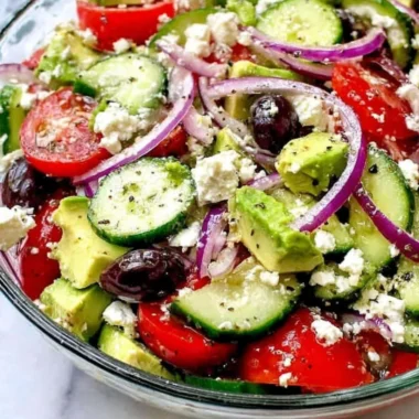 Greek salad with avocado, feta, olives, and vibrant vegetables.