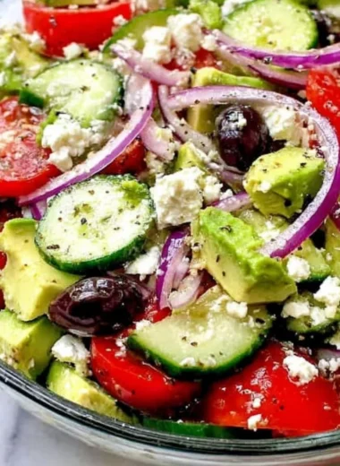 Greek salad with avocado, feta, olives, and vibrant vegetables.