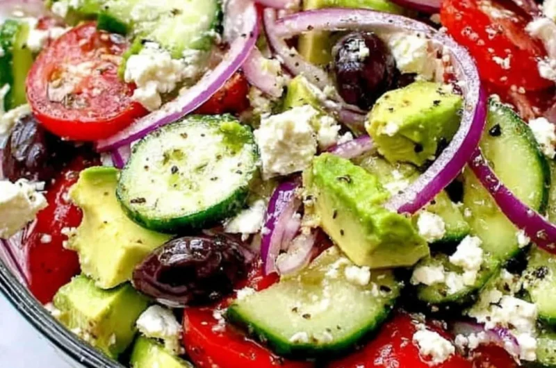 Greek salad with avocado, feta, olives, and vibrant vegetables.