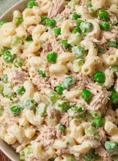 Bowl of tuna pasta salad with fresh vegetables and dressing