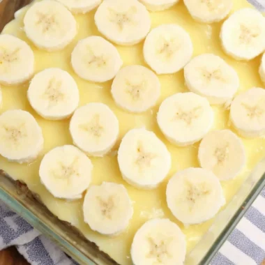 Slice of Banana Pudding Poke Cake with banana slices and whipped cream on top