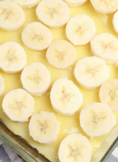 Slice of Banana Pudding Poke Cake with banana slices and whipped cream on top