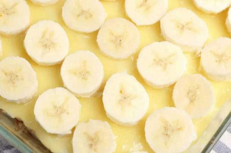 Slice of Banana Pudding Poke Cake with banana slices and whipped cream on top