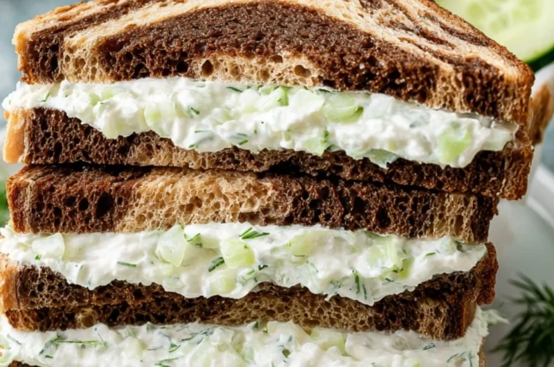Delicious cucumber sandwiches with fresh herbs and creamy spread on white bread.