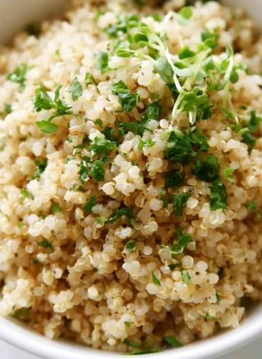 Bowl of Herb and Garlic Quinoa garnished with fresh herbs and garlic cloves.