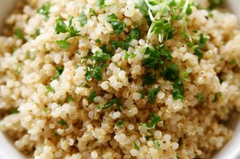 Bowl of Herb and Garlic Quinoa garnished with fresh herbs and garlic cloves.