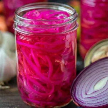 Jar of quick pickled red onions on a kitchen countertop