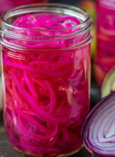 Jar of quick pickled red onions on a kitchen countertop