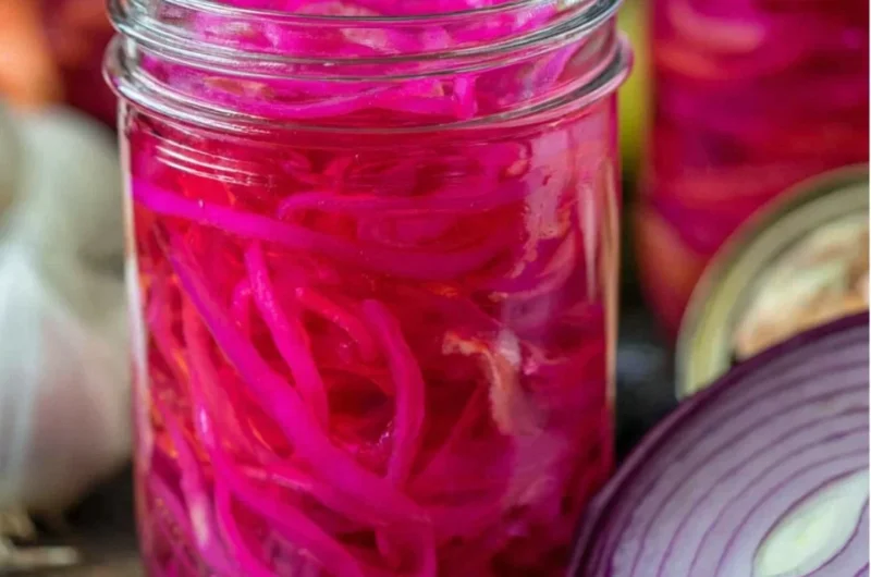 Jar of quick pickled red onions on a kitchen countertop
