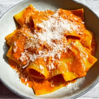 Creamy vodka pasta dish garnished with herbs and Parmesan cheese