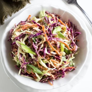Cozy coleslaw served alongside pulled pork sandwiches on a wooden table