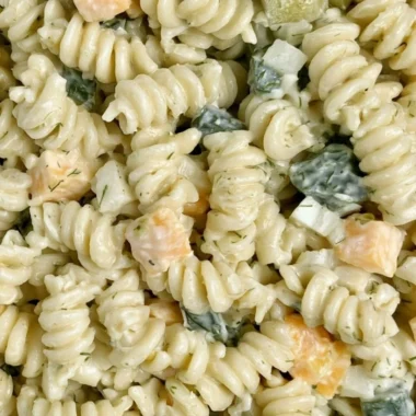 Delicious Dill Pickle Pasta Salad in a bowl, garnished with fresh herbs.