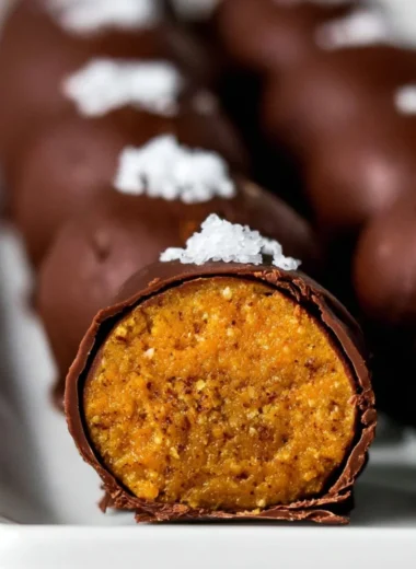 Delicious healthy pumpkin truffles topped with crushed nuts on a wooden platter
